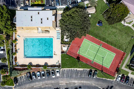 A tennis court is located next to a swimming pool.