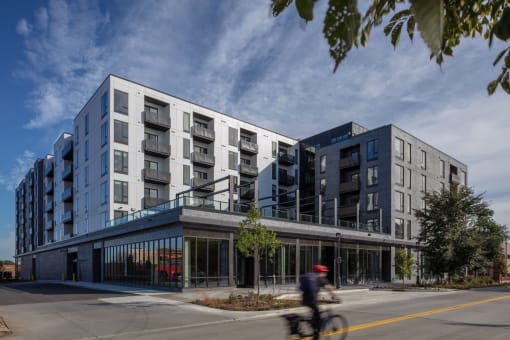 a man riding a bike down a street in front of a building at Maven on Broadway, Rochester