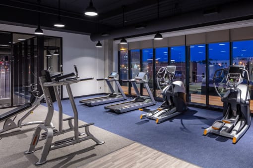 a workout room with treadmills and other exercise equipment at night