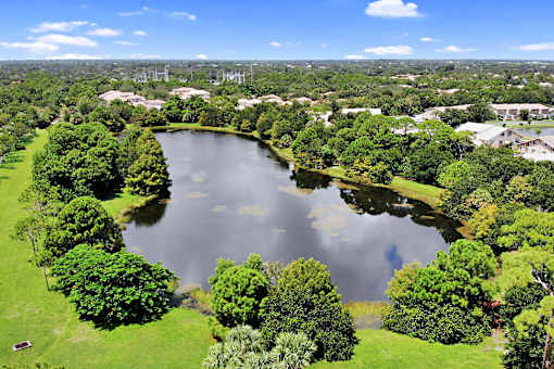 A lake surrounded by green trees and buildings in the distance.