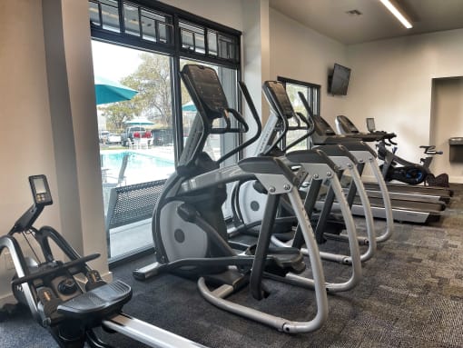 a row of treadmills and elliptical trainers in a gym