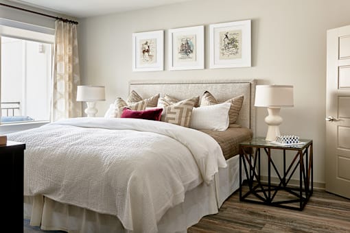A bedroom with a large bed and a window with curtains.