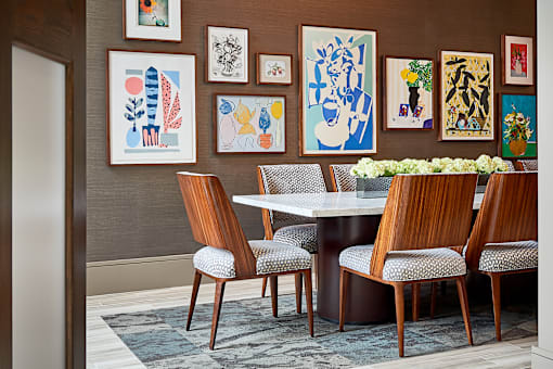 A dining room with a table surrounded by chairs and pictures on the wall.