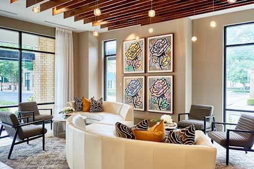 A living room with a white couch and a painting of a rose on the wall.