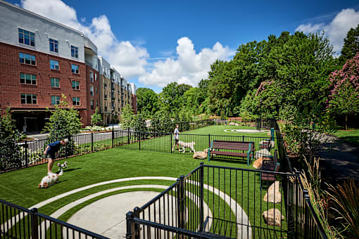 A man is playing soccer in a courtyard surrounded by a fence.