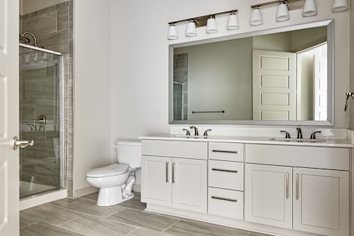 A white bathroom with a toilet, sink, and mirror.