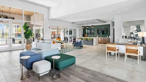 A modern living room with a white sofa, a green ottoman, and a wooden coffee table. at Lucie at Tradition Apartments, Port St. Lucie, FL