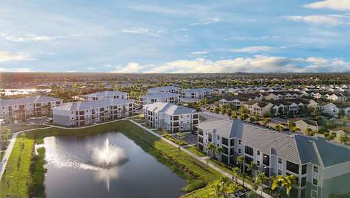 A large building complex with a fountain in the middle of a pond. at Lucie at Tradition Apartments, Port St. Lucie