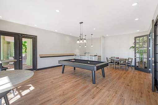 A room with a pool table and a dining table.