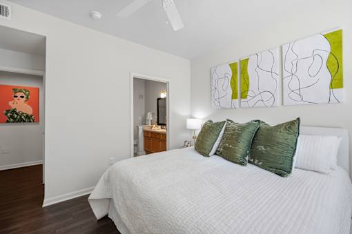 A bedroom with a bed, nightstand, and artwork on the wall.