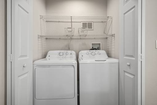 Two white washing machines in a small laundry room.