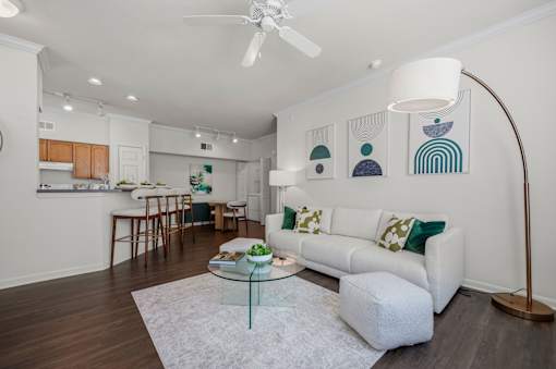 A living room with a white couch and a glass coffee table.
