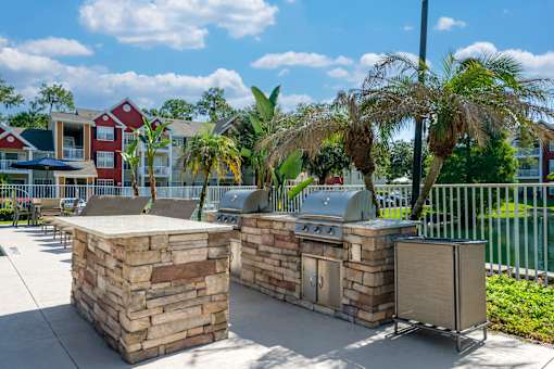 A stone barbecue area with palm trees in the background.