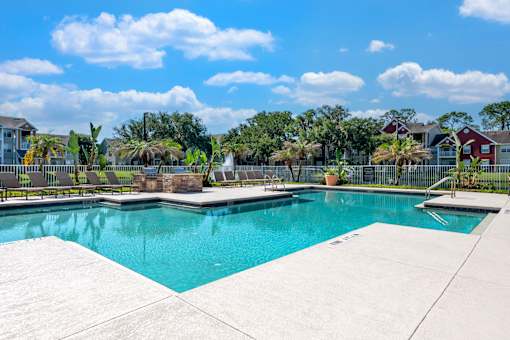A swimming pool surrounded by a concrete deck and a residential area in the background.