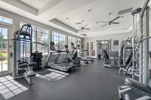 A spacious gym with various exercise equipment and a tiled floor.