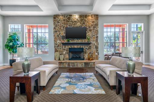 A living room with a stone fireplace and a flat screen TV mounted above it.