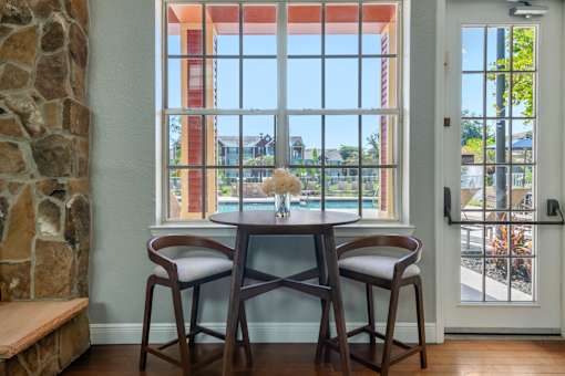 A dining room with a table and chairs in front of a large window.