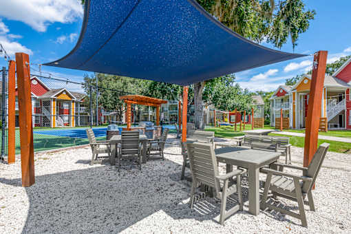 A patio with a table and chairs under a blue shade sail.
