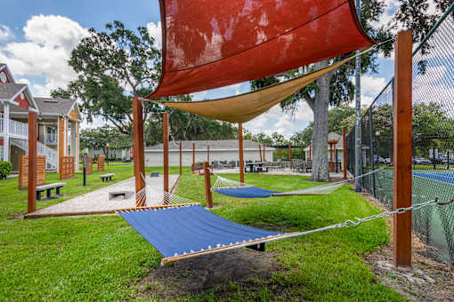 A playground with a red shade sail and a blue slide.