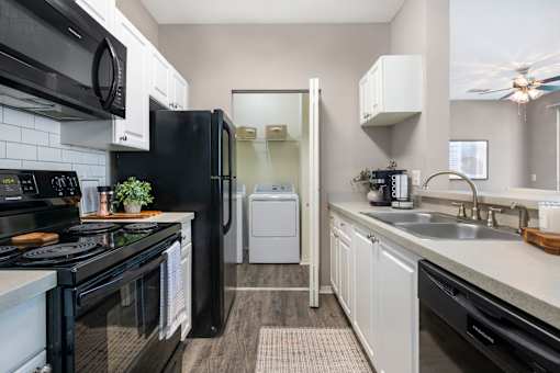 A black stove top oven sits next to a black microwave in a kitchen.