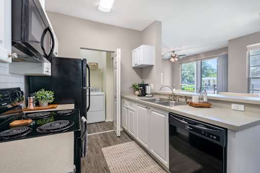 A modern kitchen with a black refrigerator and stove top oven.