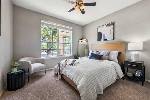 A bedroom with a large bed and a window with a view of the street outside.