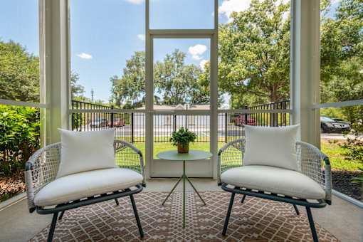 Two chairs with white cushions are placed on a patio.