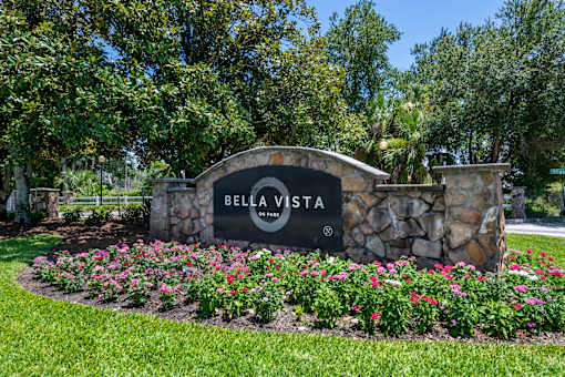 A sign that says Bella Vista in front of a green field.
