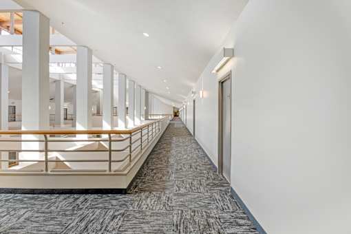 A long hallway with a carpeted floor and a railing on one side.