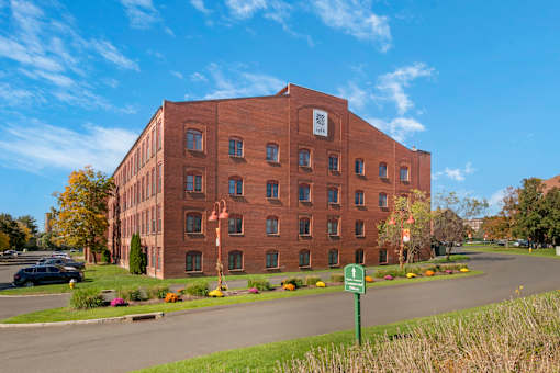 A large red brick building with a green sign in front of it.