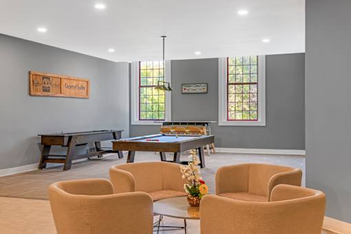 A room with a pool table and chairs.