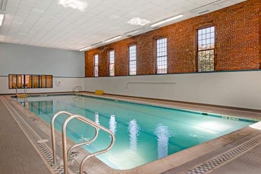A large indoor swimming pool with a brick wall and windows.