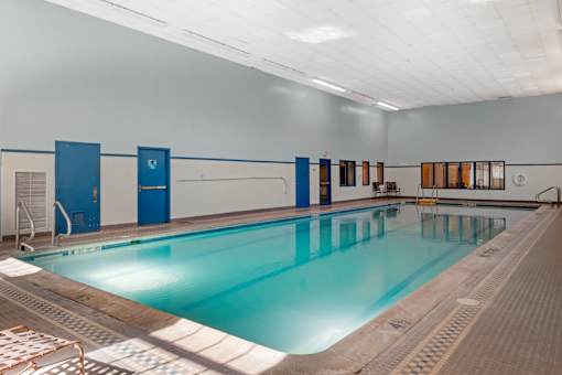 A large indoor swimming pool with a blue tiled wall and a white ceiling.
