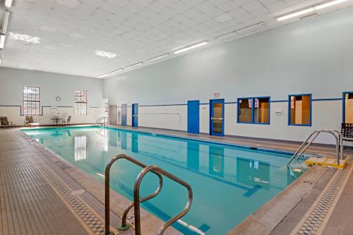 A large indoor swimming pool with a tiled floor and blue doors.