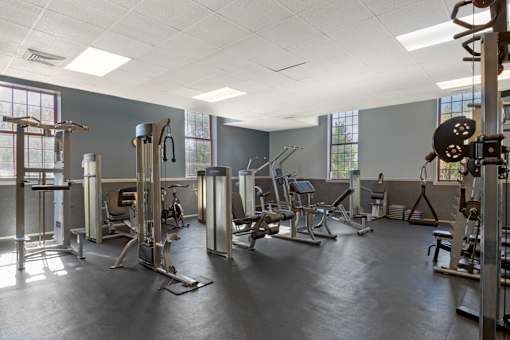 A gym with a variety of equipment including a weight bench, a leg press machine, and a cable machine.