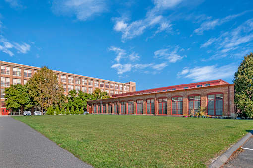 A long building with a red roof and a green lawn in front.