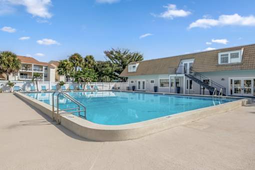 A large swimming pool in front of a building with a staircase leading down to it.