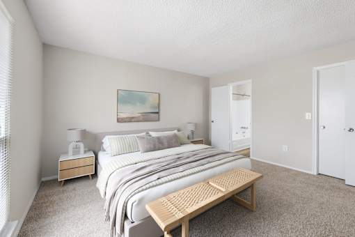 A bedroom with a large bed and a wooden bench.