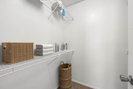 A white bathroom with a basket on the shelf.