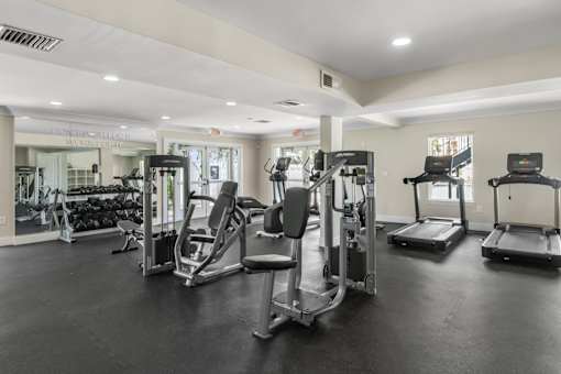 A gym with a variety of equipment including treadmills, weights, and exercise machines.
