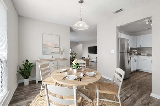 A dining room with a table set for two and a kitchen in the background.