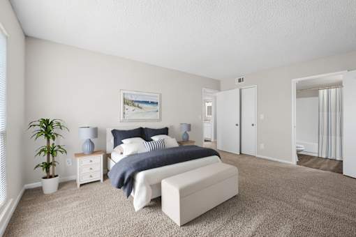 A bedroom with a bed, nightstand, and a plant.