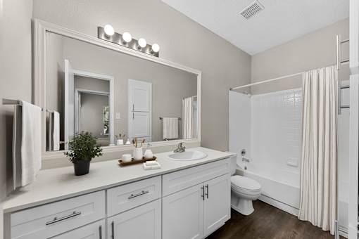 A white bathroom with a toilet, sink, and mirror.