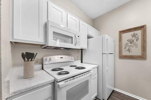 A kitchen with white appliances and cabinets.
