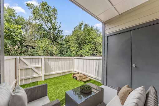 A patio with a table and chairs overlooking a fenced-in yard.