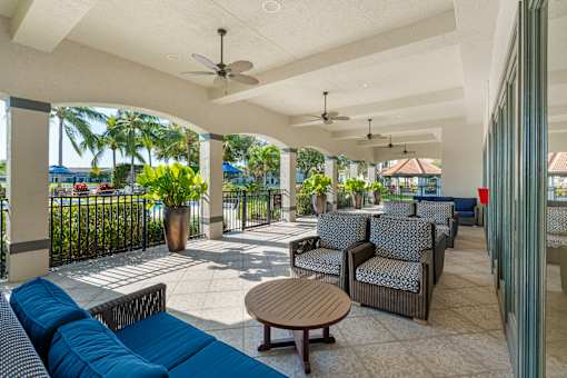 An outdoor lounge area that is covered with a ceiling and paddle fans