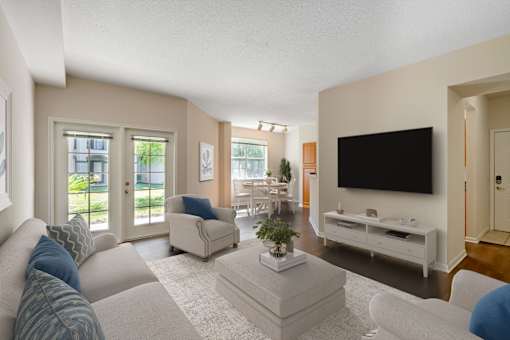 A living room with a white couch, a white coffee table, and a black television.