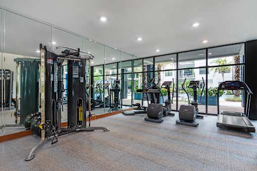 A gym with a variety of equipment including treadmills, weights, and exercise machines.
