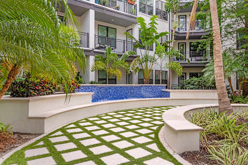A modern building with a pool and a green lawn.