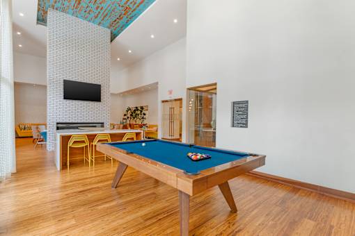 A pool table in a room with a tv and a plant.